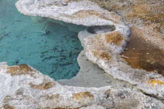 Close up of mineral deposits on the perimeter of a clear blue geyser in the Upper Geyser Basin at