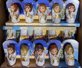 Chocolate Christmas angel in musical instruments printed on colorful staniol paper on a retail