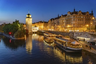 Hotel boats on the banks of the Vltava river and Sitkov water tower at dusk, Prague, Czech Republic