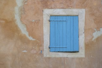 A dilapidated, blue-painted shutter on a faded wall, village of Menerbes, Luberon, Vaucluse,