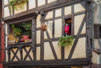 Timber-frame house decorated with vehicles in the historic old town of Riquewihr, Ellsass
