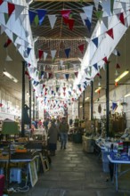 Market stalls with bunting flags inside historic Shambles market hall building, Devizes, Wiltshire,