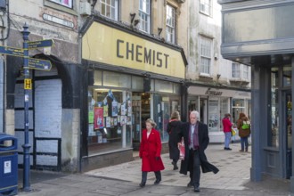 Shops and shoppers in Little Brittox street, Devizes, Wiltshire, England, UK traditional Chemist