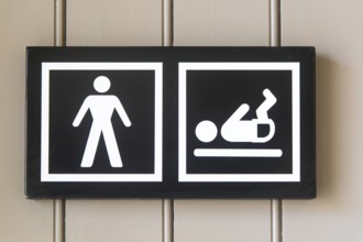 Pictogram sign for nappy changing facility in male bathroom toilets, UK