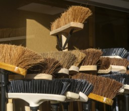 Display of bristled heads of broom brushes outside hardware shop, UK