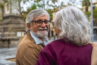 Senior man with a beard and glasses smiling warmly at his female partner, enjoying time together
