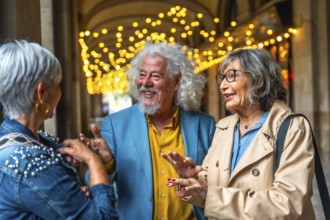 Three senior friends enjoying a lively conversation under decorative lights, sharing laughter and
