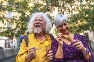Smiling senior couple sharing an outdoor date, happily eating ice cream cones, representing active