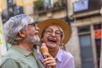 Senior couple laughing and enjoying a refreshing ice cream cone together during a relaxing summer