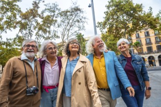 Group of smiling multi ethnic senior friends embracing, walking, and enjoying a sightseeing trip in