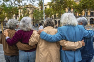 Group of diverse seniors walking together in a city, embracing with arms around each other,