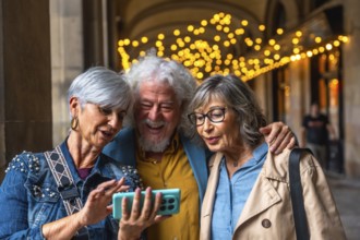 Three happy senior friends standing outdoors, looking at a smartphone screen, interacting with