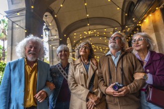 Senior friends strolling beneath a decorated arcade, smiling and looking up as they enjoy a sunny