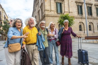 Happy senior friends walking through a sunny european city street with luggage, smiling and