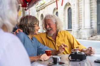 Senior friends sharing a moment of joy and laughter while having coffee at an outdoor cafe,