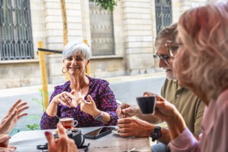 Mature adults gathering socially at an outdoor cafe, enjoying coffee and engaging in lively