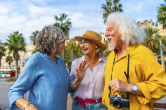 Three cheerful senior friends enjoying a lively discussion outdoors during their city vacation,