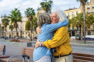Enthusiastic senior couple embracing each other with joy and affection in a city setting, enjoying