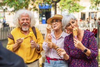 Group of happy senior friends smiling and eating ice cream cones outdoors, enjoying summer day and