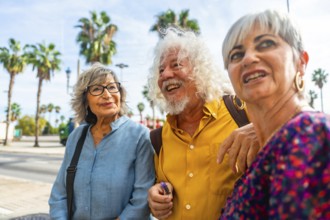 Three happy senior friends enjoying a vacation while walking together on a city street, sharing