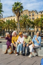 Group of happy senior friends enjoying their city vacation, sitting outdoors and laughing together