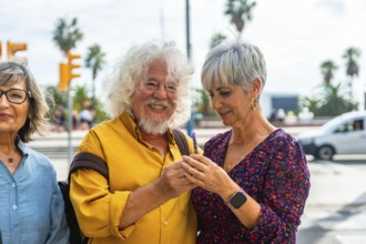 Senior couple embracing on a sunny city street, smiling and looking at a smartphone while enjoying