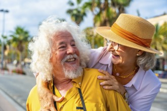 Senior couple embracing and smiling at each other outdoors on a sunny vacation, enjoying