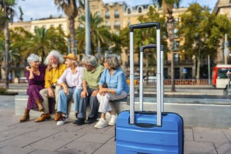 Seniors group relaxing on a bench in a city street with a blue suitcase in the foreground, enjoying