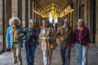 Group of five senior friends walking together arm in arm under an ornate archway with decorative