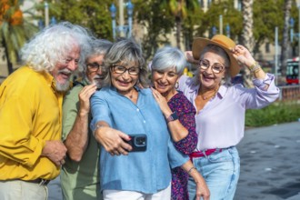 Group of five cheerful seniors enjoying leisure time together, standing close and smiling while