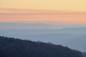 Pastel-colored silhouettes of hills and trees at sunset convey a peaceful atmosphere, Seckmauern,