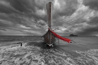 Longtail boat on the beach with dark rain clouds behind it, Koh Ngai island, Andaman Sea, Satun