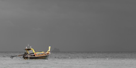 Longtail boat (Thai: Ruea Hang Yao) on the beach, behind it an approaching thunderstorm, Koh Ngai