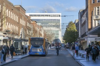 Buses and shoppers busy city centre street at Christmas, High Street, Exeter, Devon, England, UK