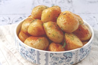 Baked new potatoes, with butter and dill, on a white plate, at home, no people