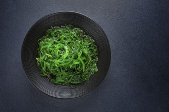 Chuka salad, made from fresh seaweed, with sesame dressing, served in a black bowl