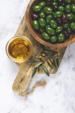 Chalkidiki olives, classic Greek green olives, in a bowl on a cutting board, top view, without