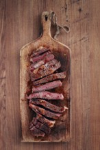 Medium rare, sliced rib eye steak, grilled cowboy steak, on a chopping board, close-up, homemade,