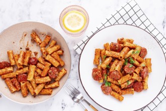 Rigatoni pasta with spicy sausage, and rich tomato sauce served, on a white plate, homemade