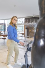 Woman in a museum interacting with technology next to a statue, robotic personality Roboloutions in