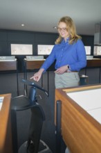A woman wearing a blue shirt interacts with a screen in the museum, robotic personality
