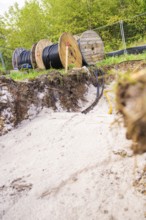 Trench with cable rolls in the foreground and construction work in the background, PV