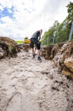 A man works with a shovel in a ditch on a construction site under cloudy skies, Bau PV