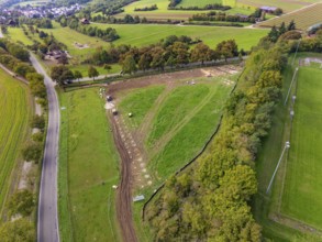 Green landscape with roads, fields and a small village in the background, PV Freifaechenanlage