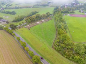 Aerial view of a green landscape with construction site and adjacent road, PV Freifaechenanlage