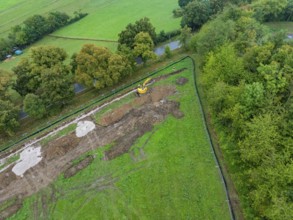 Aerial view of a construction site with excavator in a green field landscape, Bau PV