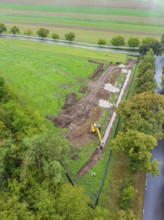 Aerial view of a construction site with excavator in a green landscape in autumn, construction of a