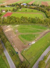 Aerial view of a green landscape with tennis court and surrounding trees, PV Freifaechenanlage