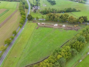 Aerial view of a green area with construction and surrounding trees, PV Freifaechenanlage