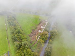 Fog-covered aerial view of a construction site with excavator in rural area, PV open-air plant